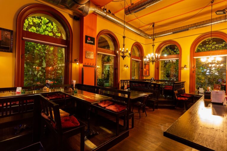 Dining room at Mariahilferbräu with arched windows, chandeliers and wooden benches